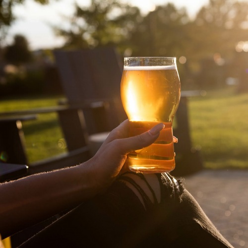 Outdoor Courtyard resident sits in chair, holding a glass of beer in outdoor courtyard